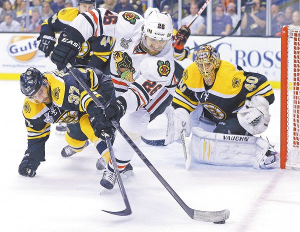 Bruins center Patrice Bergeron and Blackhawks center Michal Handzus fight for the puck in front of Bruins goalie Tuukka Rask during the first period in Game 6.